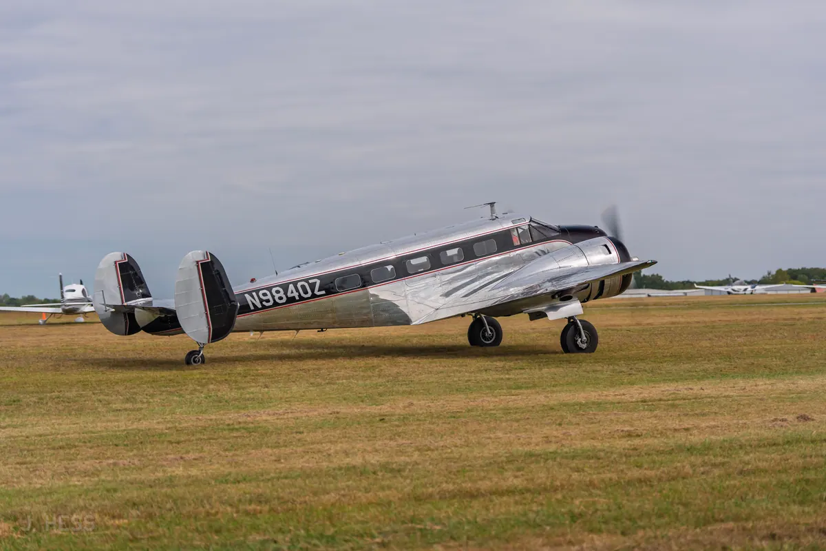 A polished Twin Beech, registration N9840Z, taxiing across the grass under an overcast sky